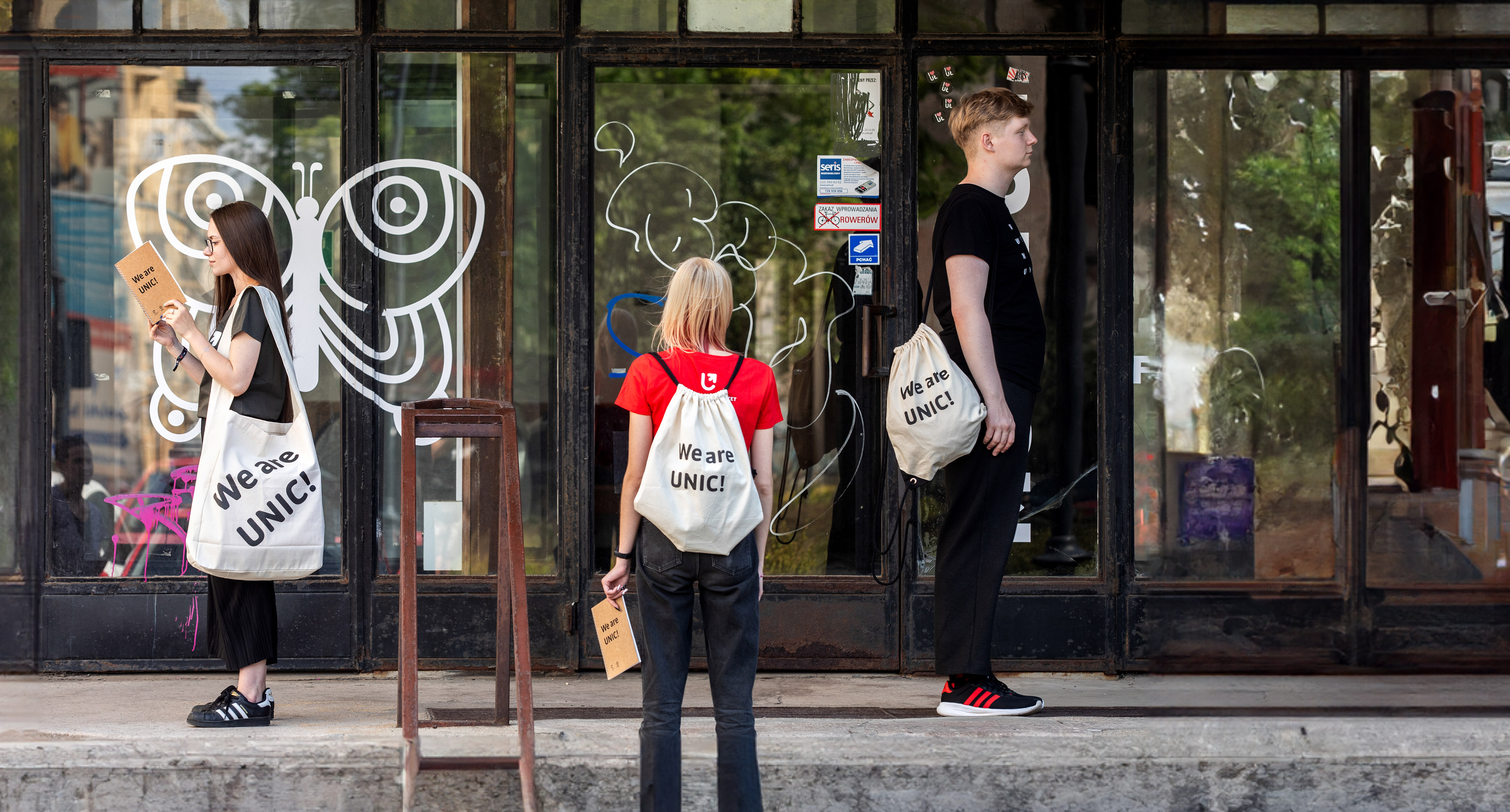 Troje studentów stojących na schodach z torbami i plecakami z projektu UNIC