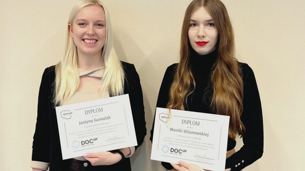 A photo of the winners of the DocUp 2023 competition. The two women standing and holding their diplomas
