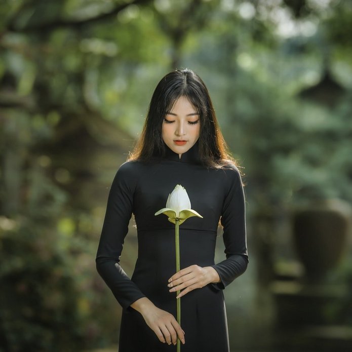 Młoda dziewczyna trzyma biały kwiat. Zdjęcie poglądowe.