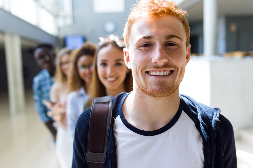 Grupa uśmiechniętych studentów stojących w rzędzie