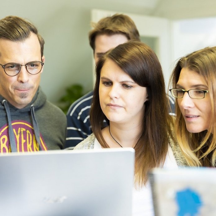 Grupa młody osób spoglądająca w ekran laptopa