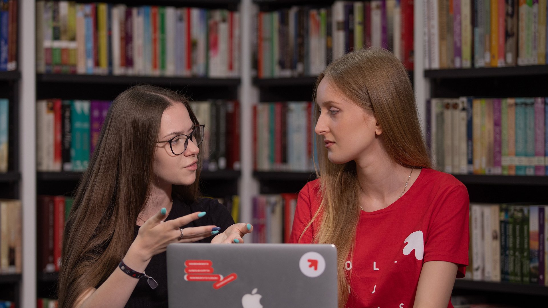 Dwie studentki dyskutują w bibliotece