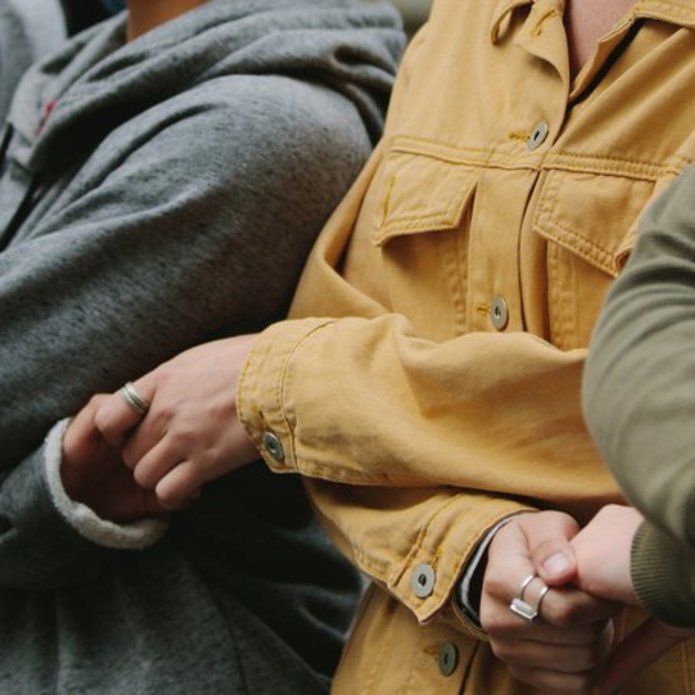 Osoby stojące obok siebie i trzymające się za ręce 