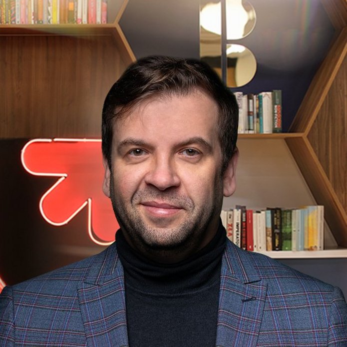 Prof. Chomczyński na tle regałów bibliotecznych i neonu z logotypem UŁ