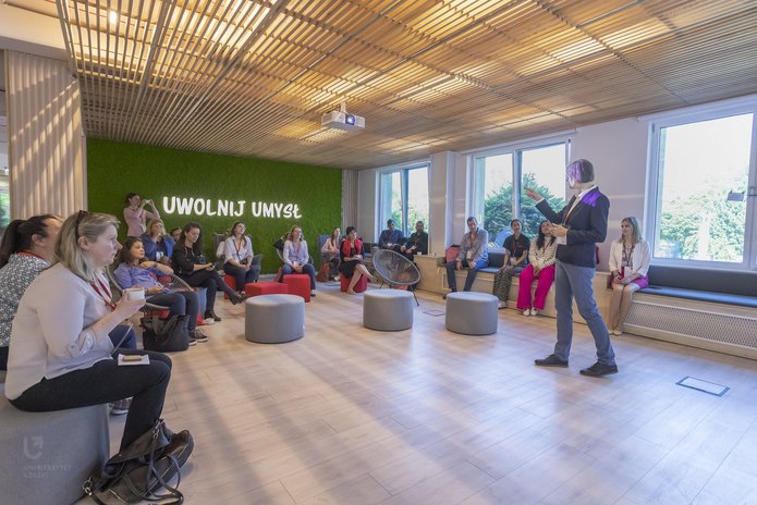 uczestnicy spotkania słuchający wykładu Liliany Lato w sali z napisem Uwolnij umysł