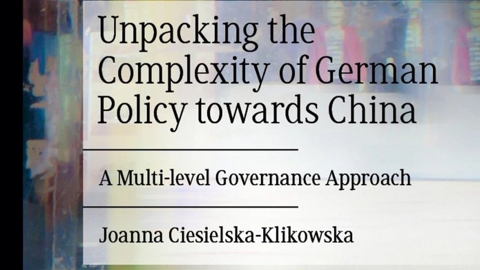 [Translate to English:] Okładka książki „Unpacking the Complexity of German Policy towards China: A Multi-level Governance Approach” autorstwa Joanny Ciesielskiej-Klikowskiej, wydanej przez Palgrave Macmillan. Tło przedstawia abstrakcyjną, kolorową kompozycję z refleksami i rozmytymi sylwetkami, symbolizującą złożoność polityki międzynarodowej i wielopoziomowego zarządzania.