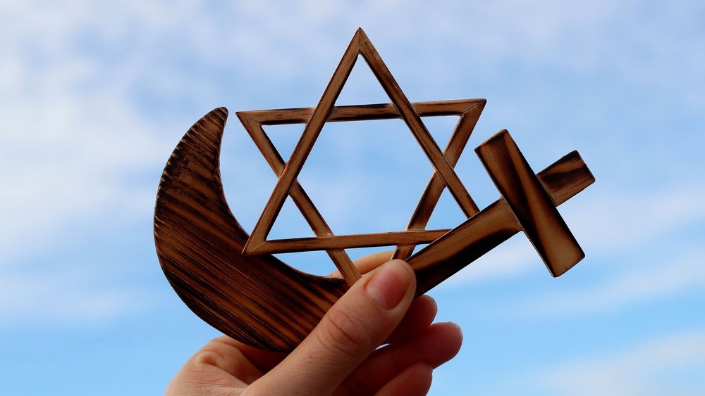 dłoń trzymające symbole różnych wyznań religijnych
