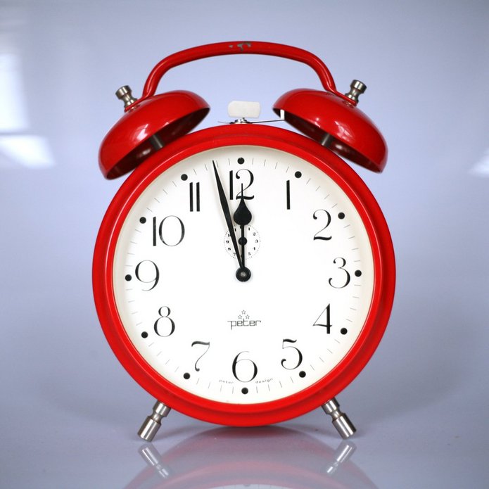 Red alarm clock, the time is three to twelve