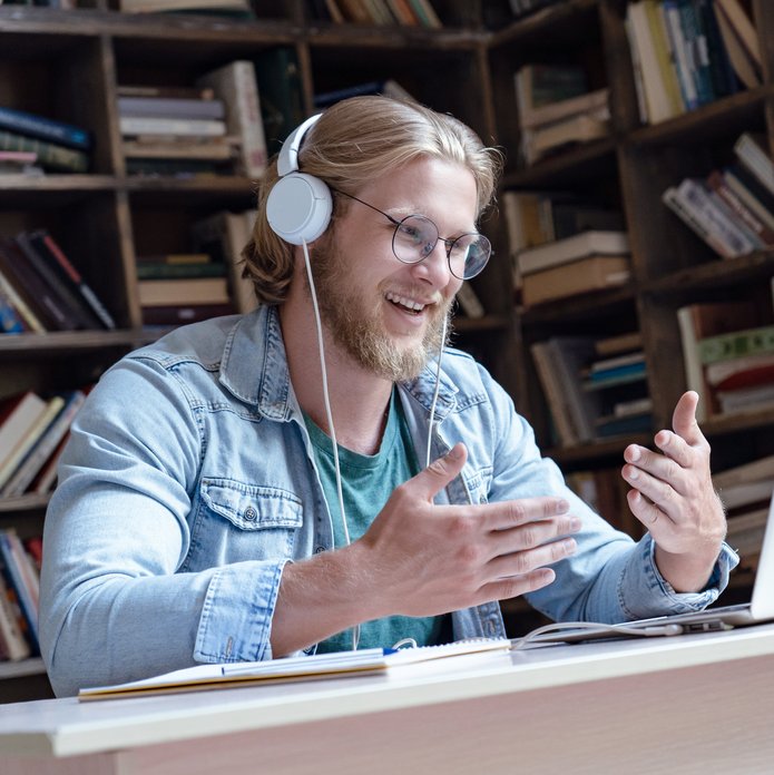 mężczyzna w słuchawkach mówiący do laptopa