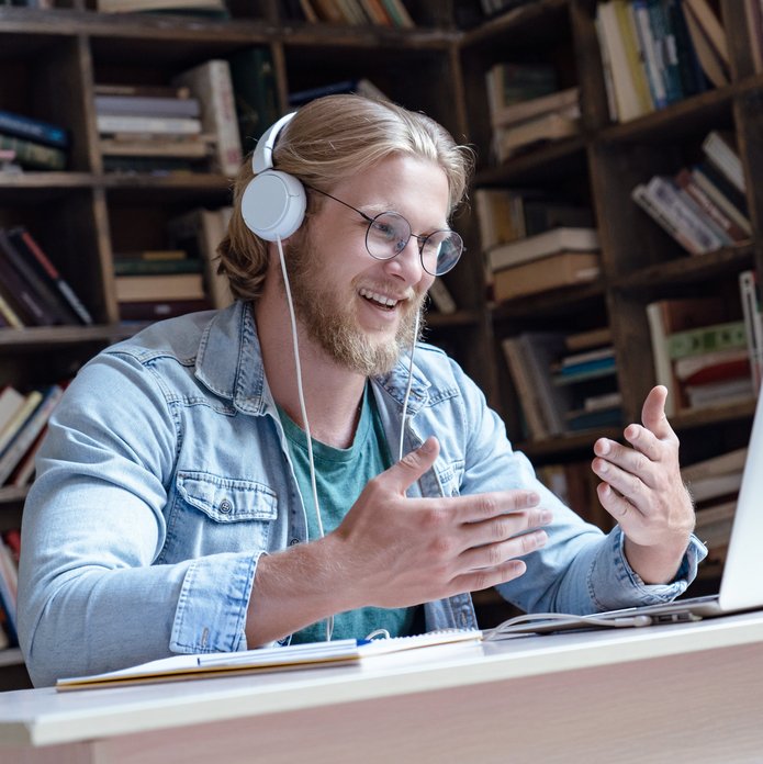 mężczyzna w słuchawkach mówiący do otwartego laptopa