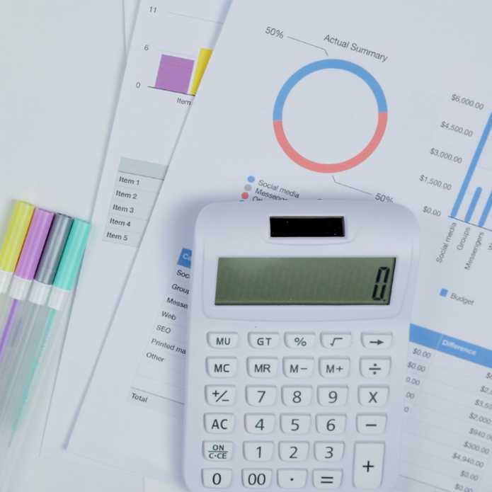 kartki z wykresami, flamastry oraz kalkulator leżące na szarym stole