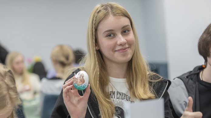 A student holding an Easter egg that she prepared earlier
