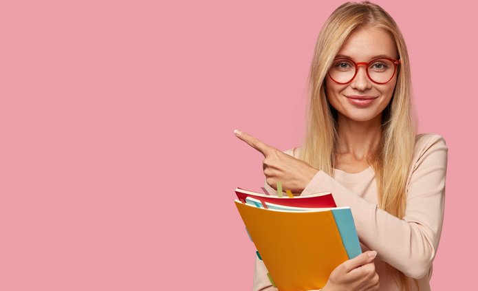 Zdjęcie-uśmiechnięta studentka trzyma trzy kolorowe zeszyty