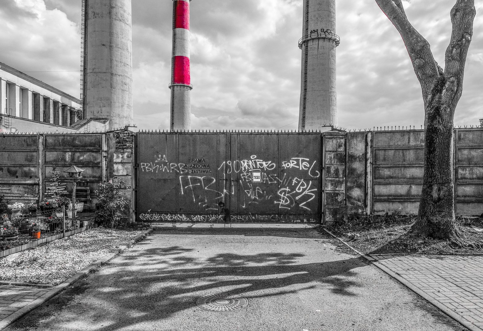 Zaniedbana i pomazana brama w tle kominy elektrociepłowni