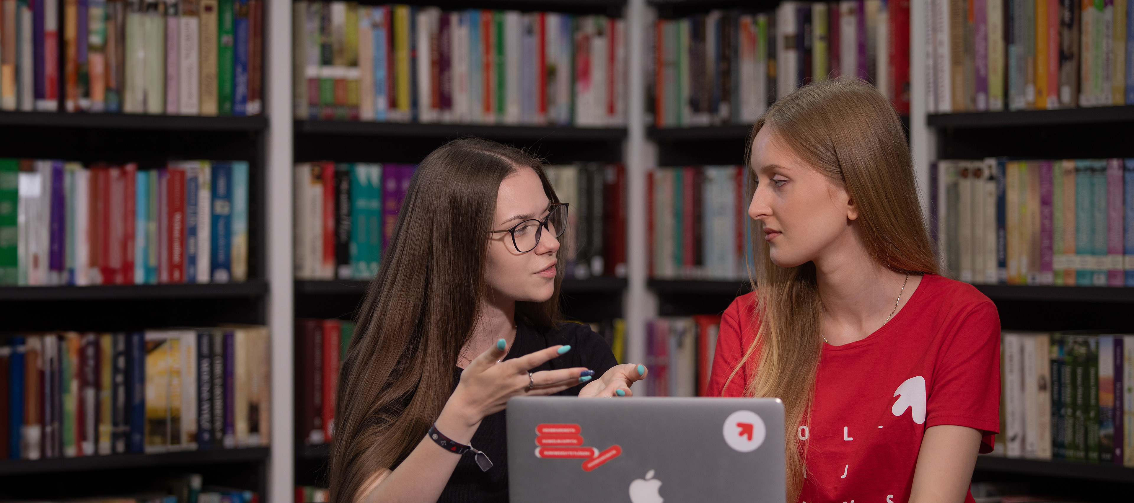 Dwie studentki dyskutują w bibliotece