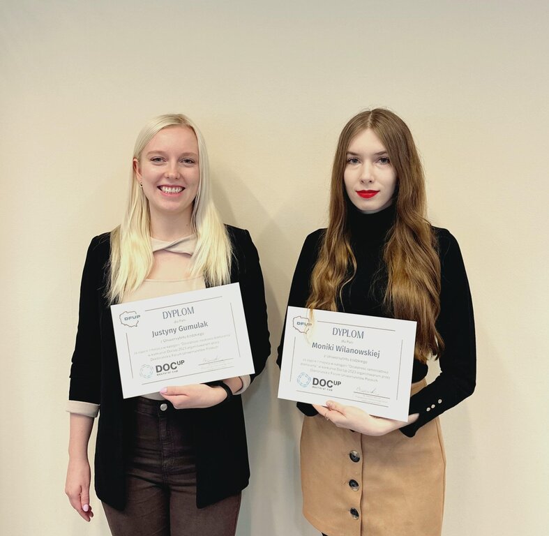 A photo of the winners of the DocUp 2023 competition. The two women standing and holding their diplomas
